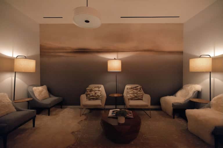 Spa relaxation lounge with beige armchairs, pendant lamps, fireplace, and neutral earth tones