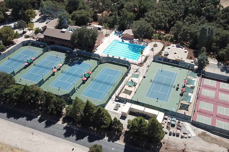 Aerial view of resort with Olympic swimming pool, tennis courts, and surrounding forested landscape