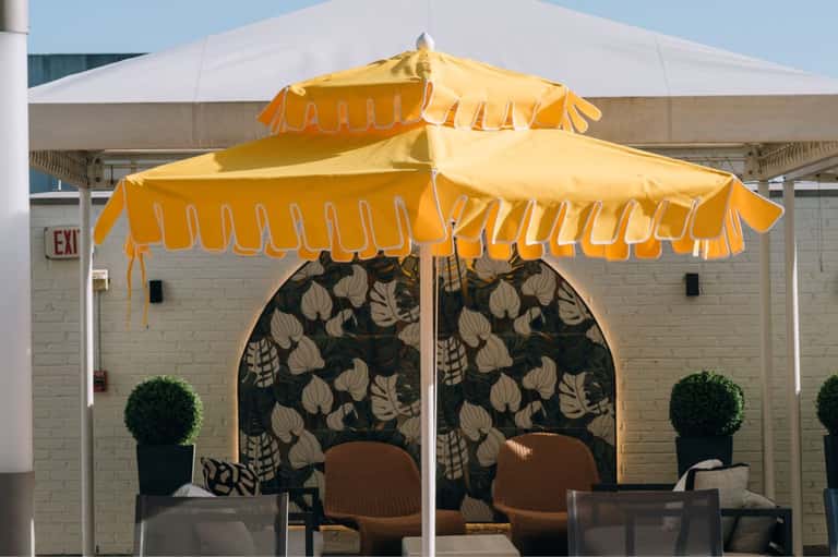 Restaurant patio with yellow scalloped umbrellas, patterned backdrop, and outdoor dining setup