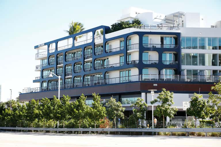 Modern multi-story residential building with distinctive blue curved facade and balconies