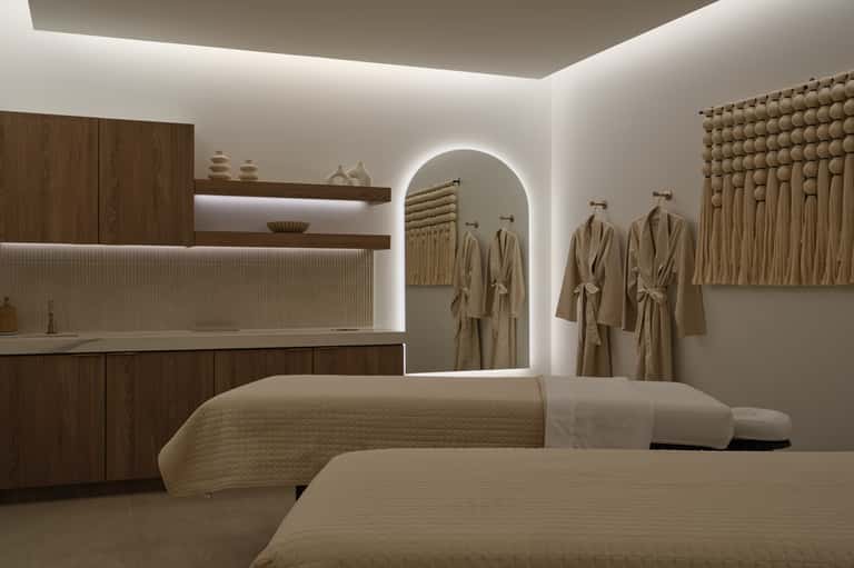 Luxury spa treatment room with wooden accents, white robes, and ambient lighting