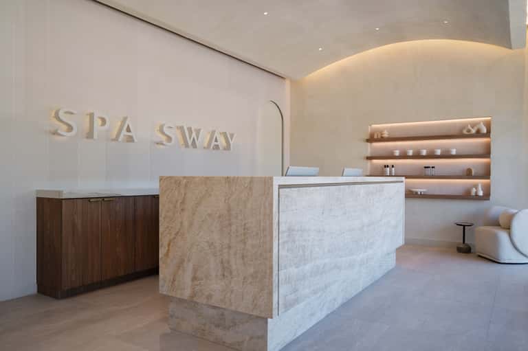 Modern spa reception desk with marble counter, wooden cabinetry, and ambient lighting