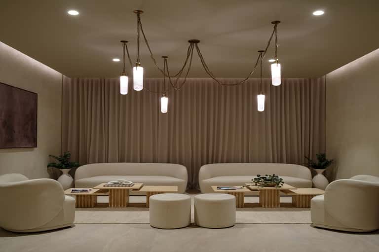 Elegant lounge with curved cream sofas, pendant lighting, wooden accents, and modern design