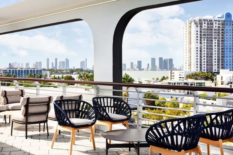 Waterfront balcony with modern seating overlooking city skyline and bay with palm trees