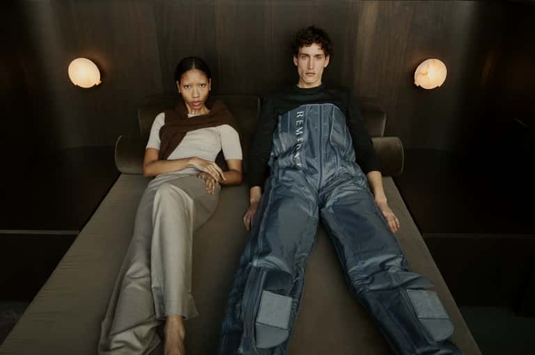 Two people lying on modern bed in minimalist hotel room with wall sconces