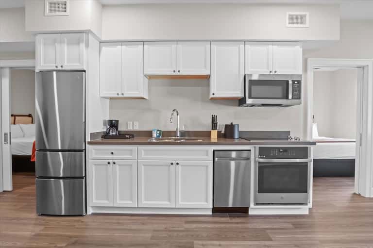 Modern kitchen with white cabinetry, stainless steel appliances, and wood countertops