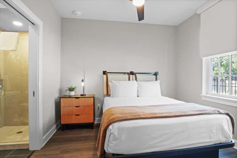 Contemporary bedroom with orange nightstand, modern headboard, and en-suite bathroom