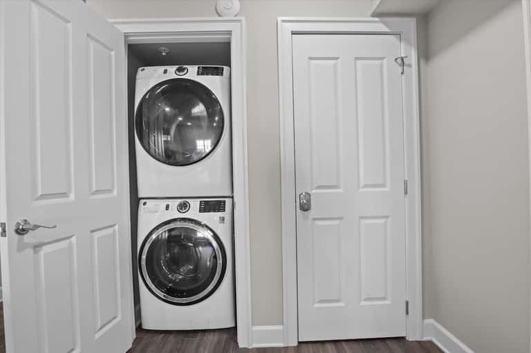 Stacked washer and dryer units in white laundry room closet