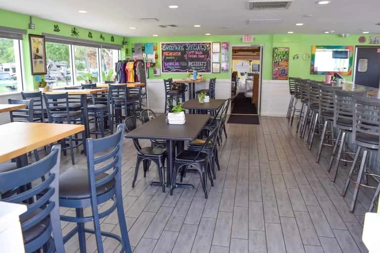Casual dining area with green walls, black chairs, and display cases