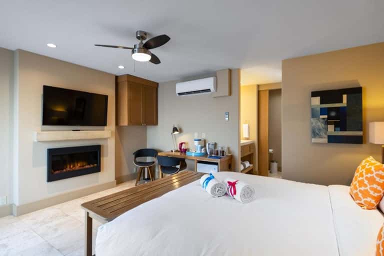 Modern hotel room with fireplace, flat-screen TV, work desk, and queen bed