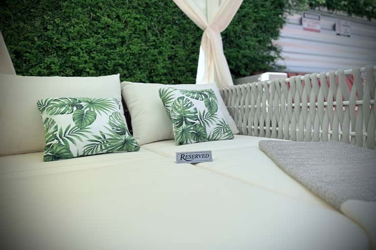 Reserved outdoor lounge seating with green leaf patterned pillows and white canopy