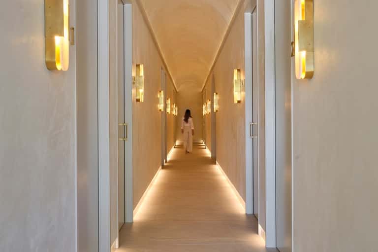 Modern hotel corridor with wooden walls, geometric ceiling, and warm wall lighting