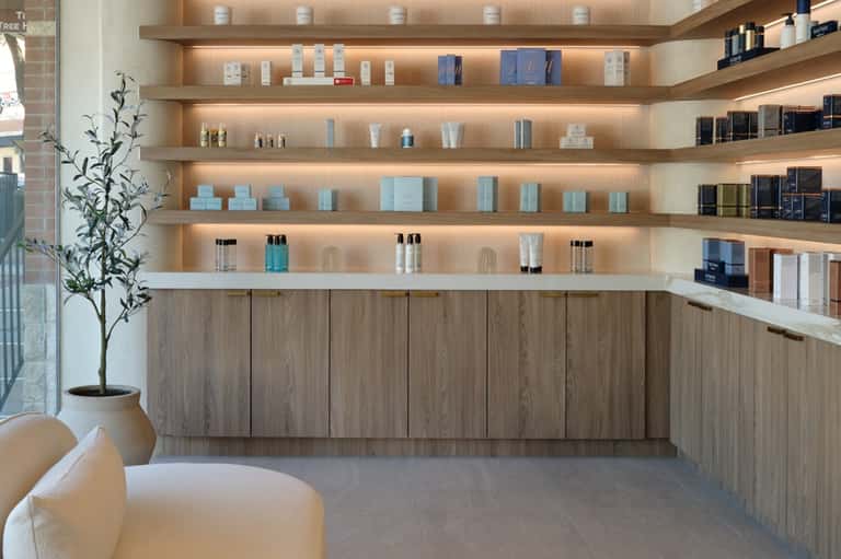 Modern spa retail display with illuminated wooden shelves stocked with skincare products