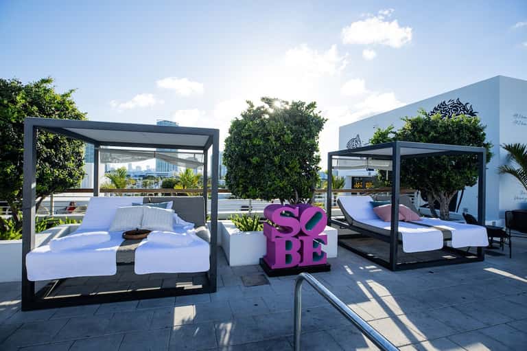 Rooftop lounge with canopy beds, city skyline views, and modern furnishings