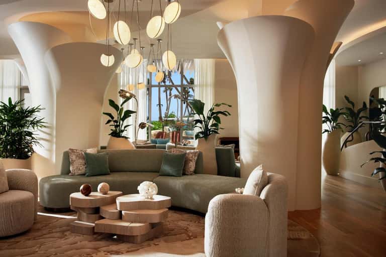 Elegant modern lobby with curved columns, pendant lighting, green sofa, and potted plants