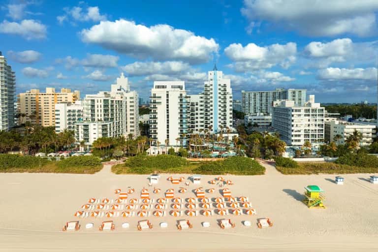Aerial view of Miami beach with rows of colorful umbrellas and high-rise buildings