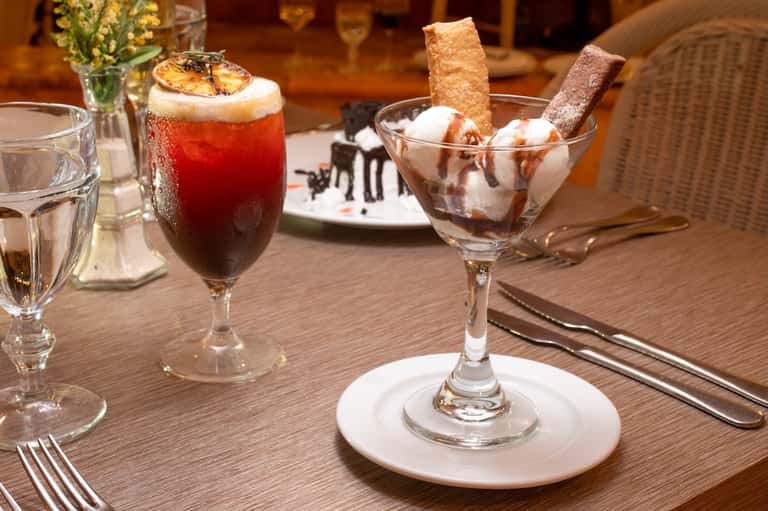 Fine dining table setting with craft cocktails, dessert, and fresh flowers