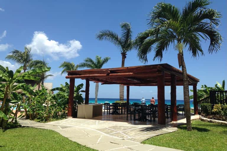 Oceanfront beach pavilion with dark wood pergola and dining table setup