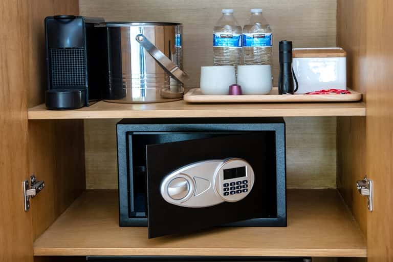In-room safe in wooden cabinet with coffee maker and bottled water amenities