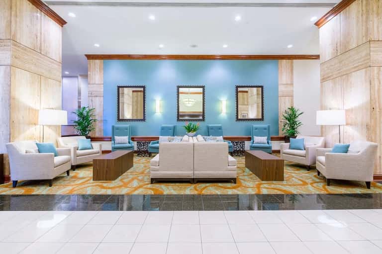 Modern hotel lobby with turquoise accent wall, cream furnishings, and decorative mirrors
