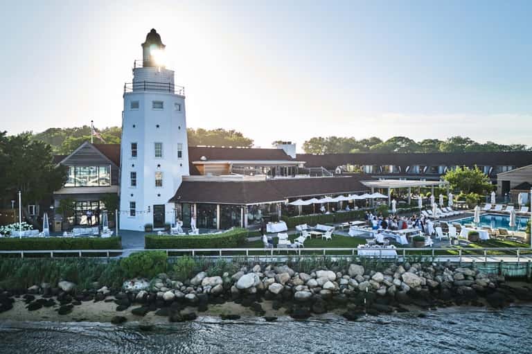 Coastal resort featuring white lighthouse tower, waterfront pools, and stone breakwater