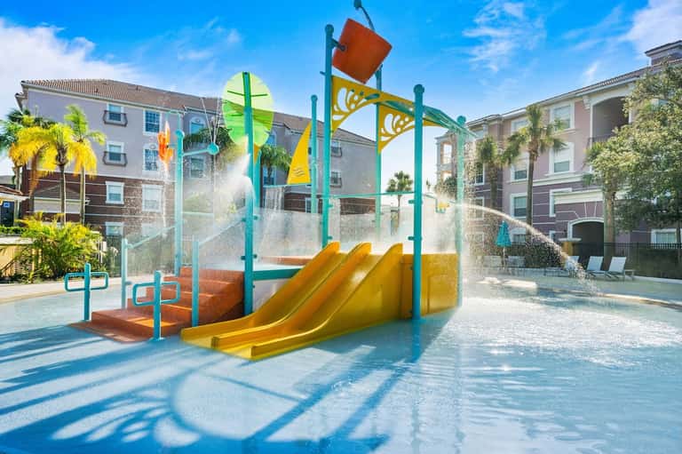 Colorful splash pad with slide for children at resort courtyard