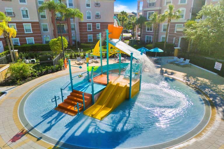 Colorful splash pad with water features and slides in residential courtyard