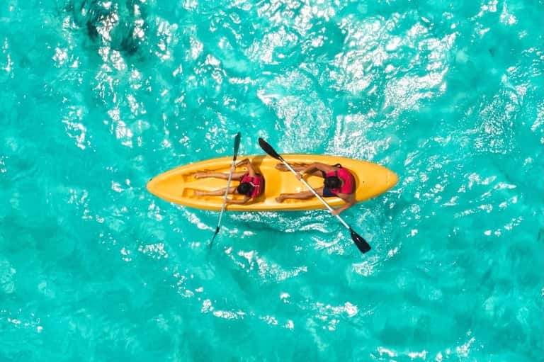 Overhead view of yellow kayak with two people on turquoise tropical water