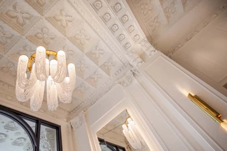 Elegant ornate ceiling with decorative molding and modern crystal chandelier lighting