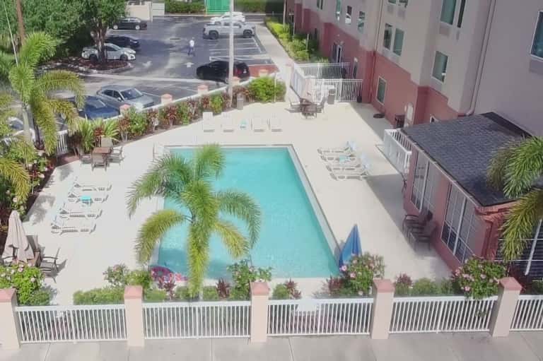 Aerial view of resort pool surrounded by palm trees and residential buildings