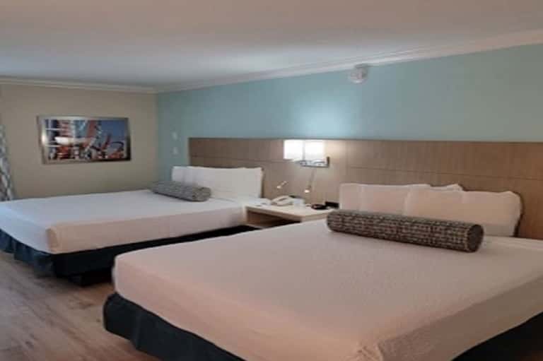 Hotel room with two queen beds, turquoise and beige color scheme, and neutral modern furnishings