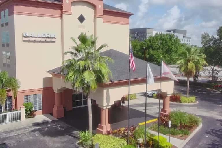Red and cream hotel building exterior with palm trees and American flag