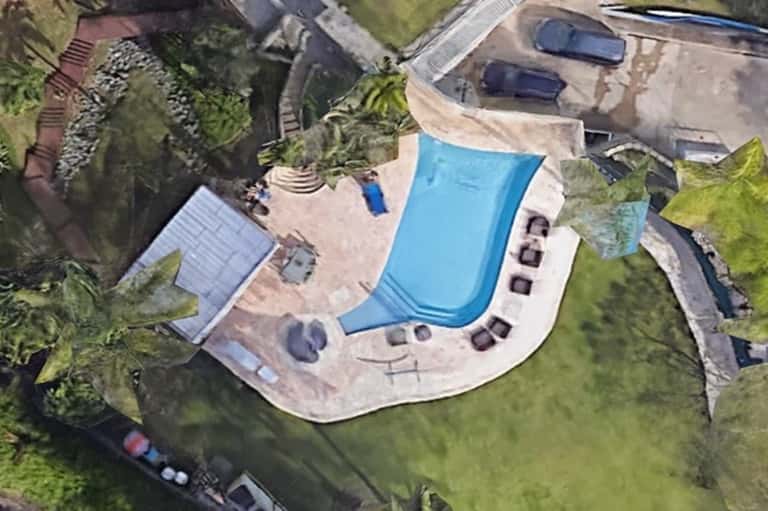 Aerial view of kidney-shaped resort pool with lounge chairs and surrounding landscaping