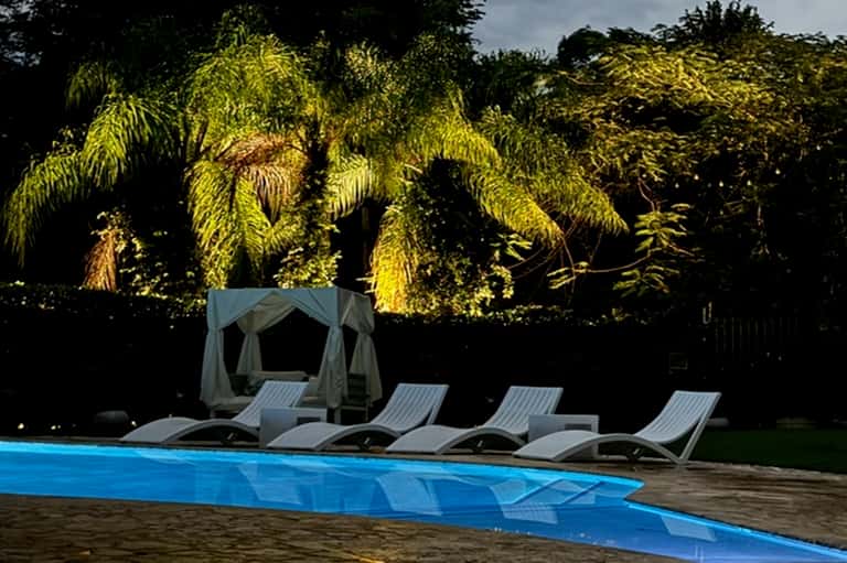 Poolside loungers and canopy by lush tropical vegetation and garden