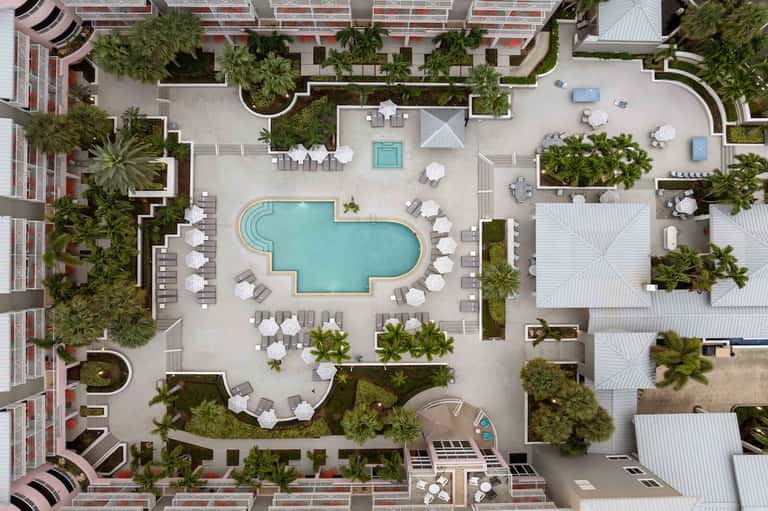 Overhead view of resort courtyard with curved pool, lounge chairs, and tropical landscaping