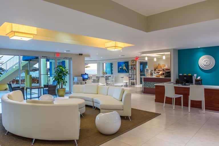 Hotel lobby with modern furnishings, turquoise accent wall, curved seating, and reception desk area
