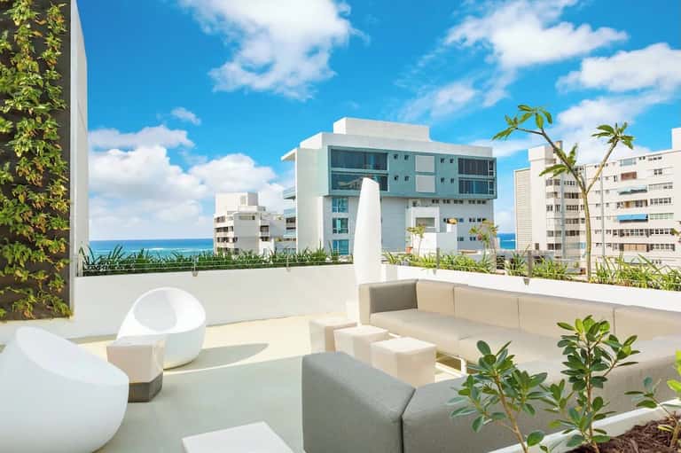 Modern rooftop lounge with cream seating, ocean views, and contemporary architecture