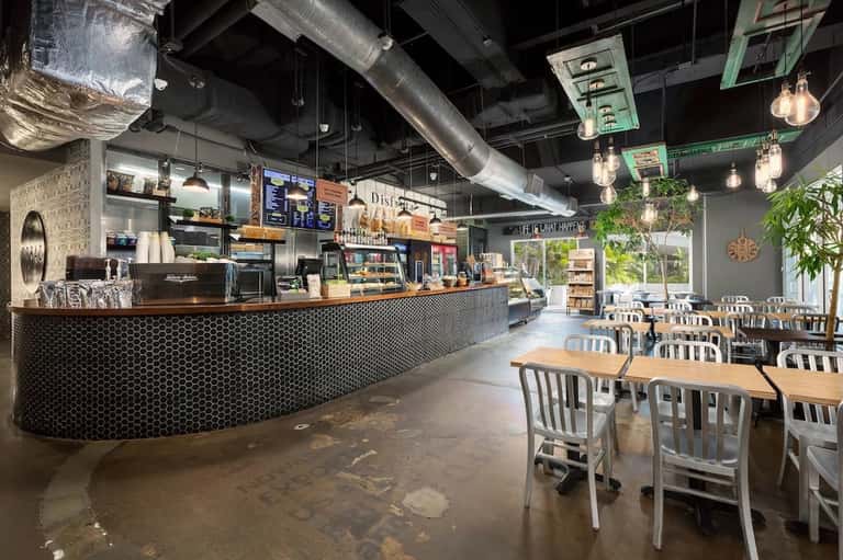 Modern cafe counter with hexagonal tile backdrop, pendant lighting, and dining area