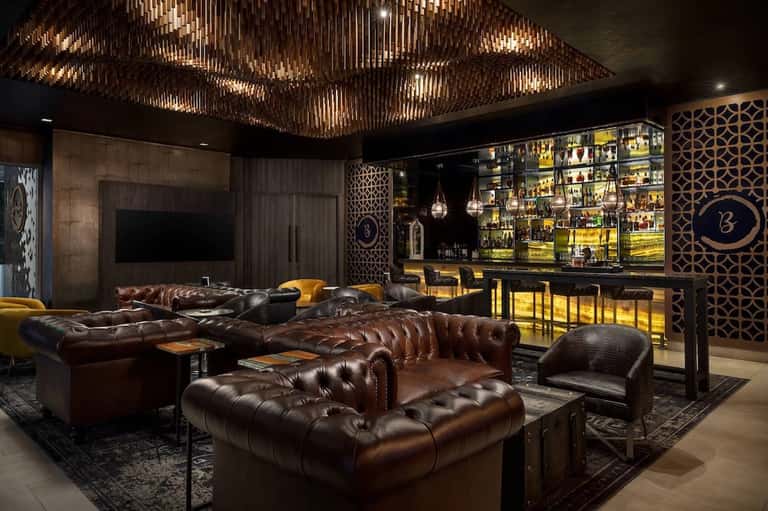 Luxury home theater with leather seating, gold ceiling fixture, and backlit bar