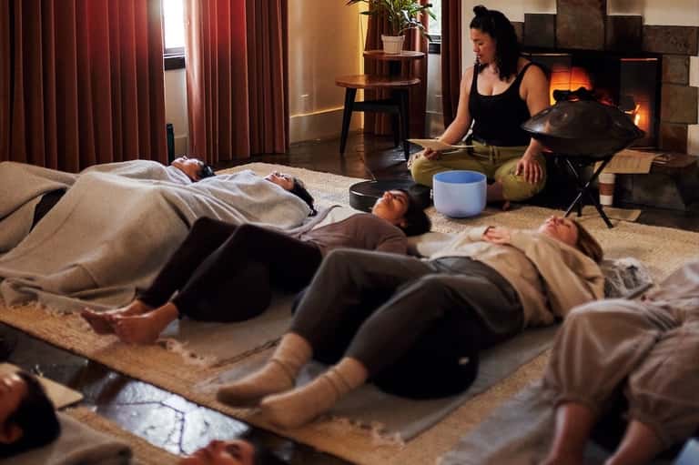 Spa wellness session with therapist performing sound bath treatment on guests indoors