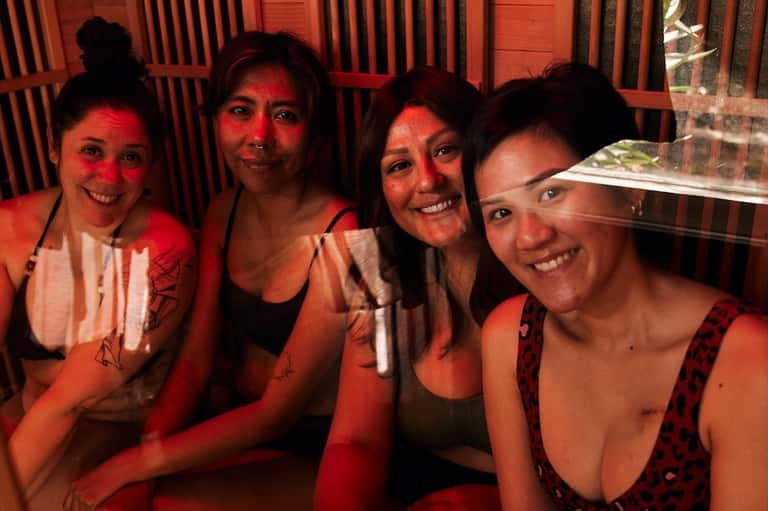 Group of four guests enjoying drinks and socializing in hotel bar with red ambient lighting