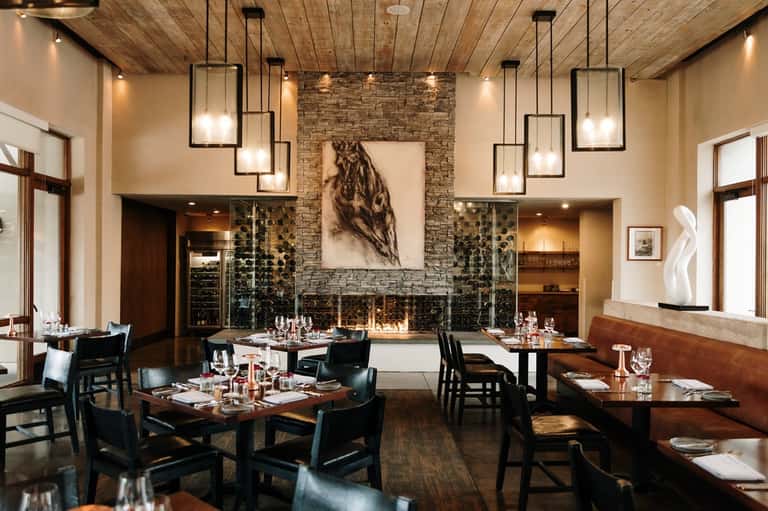 Fine dining restaurant with fireplace, wooden ceiling, and elegant table settings