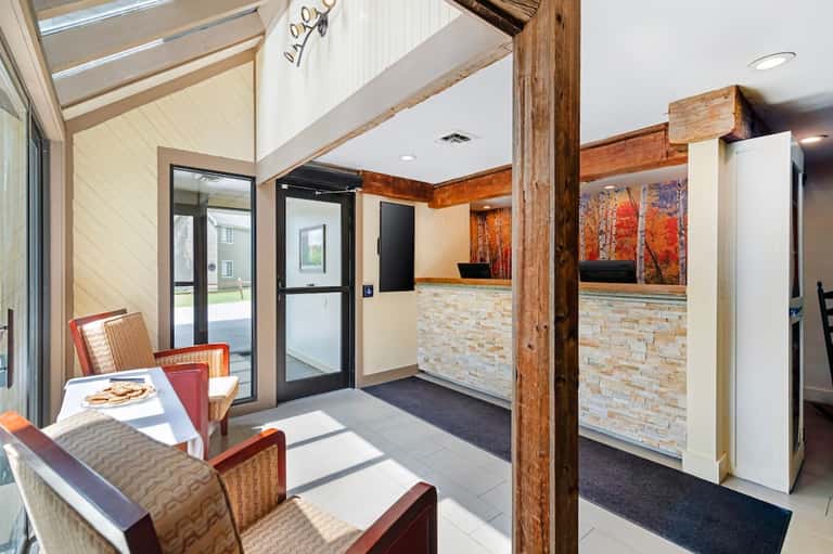 Modern hotel lobby with vaulted ceiling, exposed wooden beams, stone accent wall, and contemporary seating