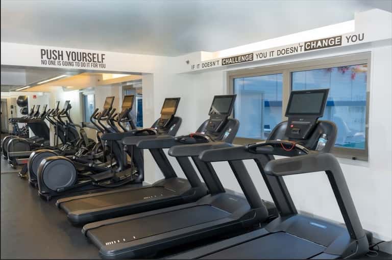Modern gym with treadmills, elliptical machines, and motivational wall signage