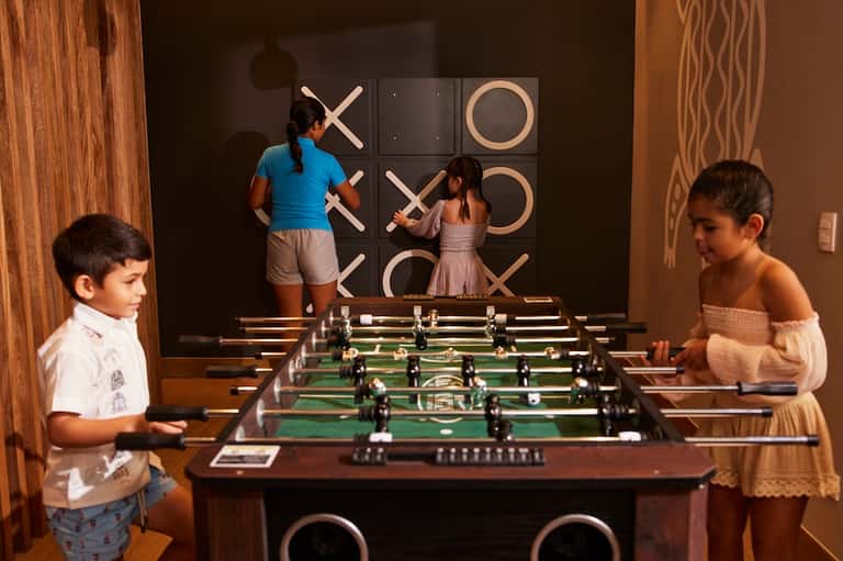 Recreation room with foosball table and large tic-tac-toe wall game, children playing