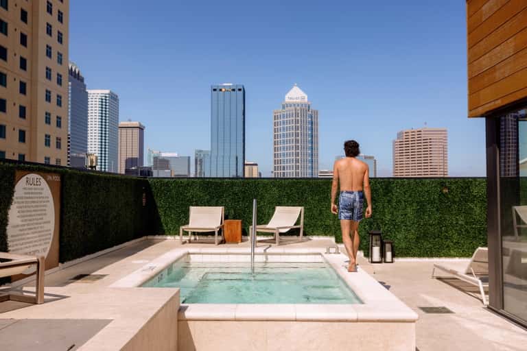 Rooftop pool deck with modern lounge chairs overlooking urban city skyline