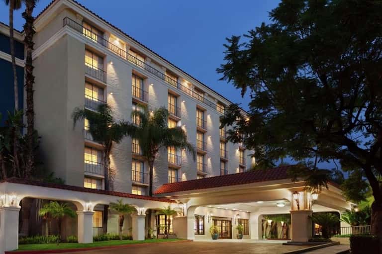 Colonial-style hotel building illuminated at dusk with white façade, palm trees, and manicured grounds