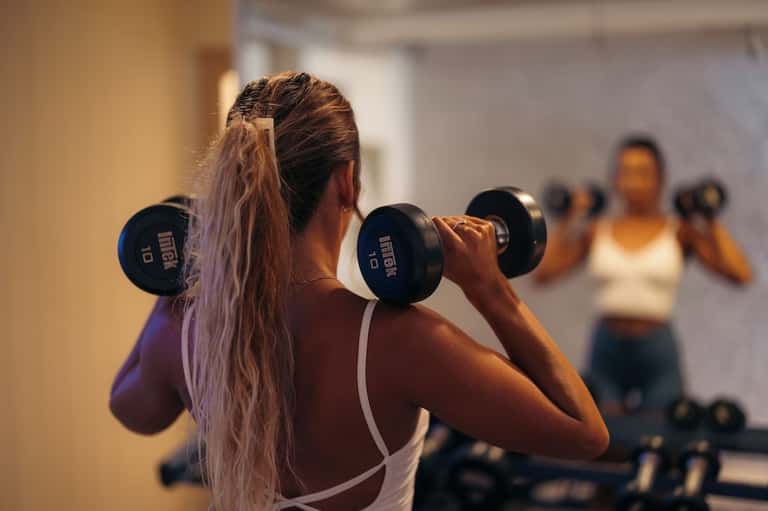 Woman lifting dumbbells during group fitness class with blurred participants in background