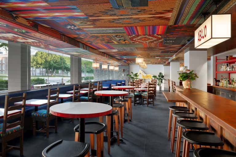 Colorful dining room with red and white round tables, striped ceiling, and bar counter