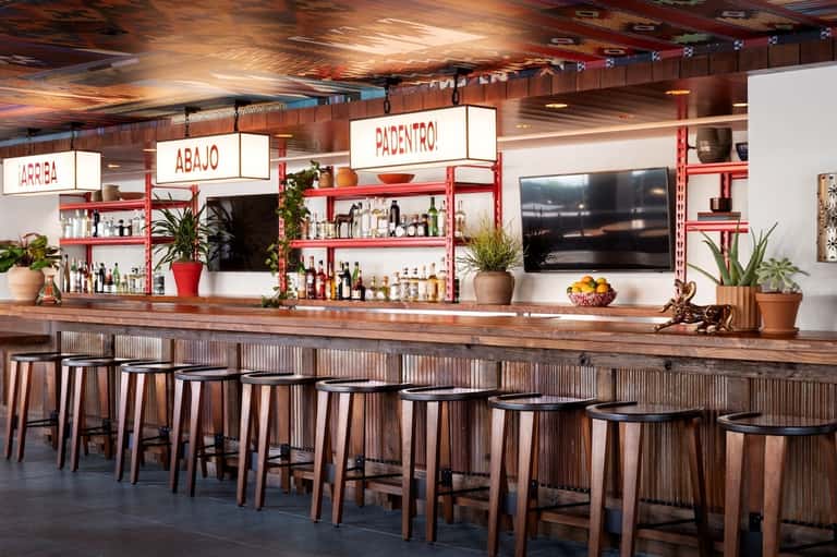 Contemporary restaurant bar with red and white design, wooden seating, and shelving